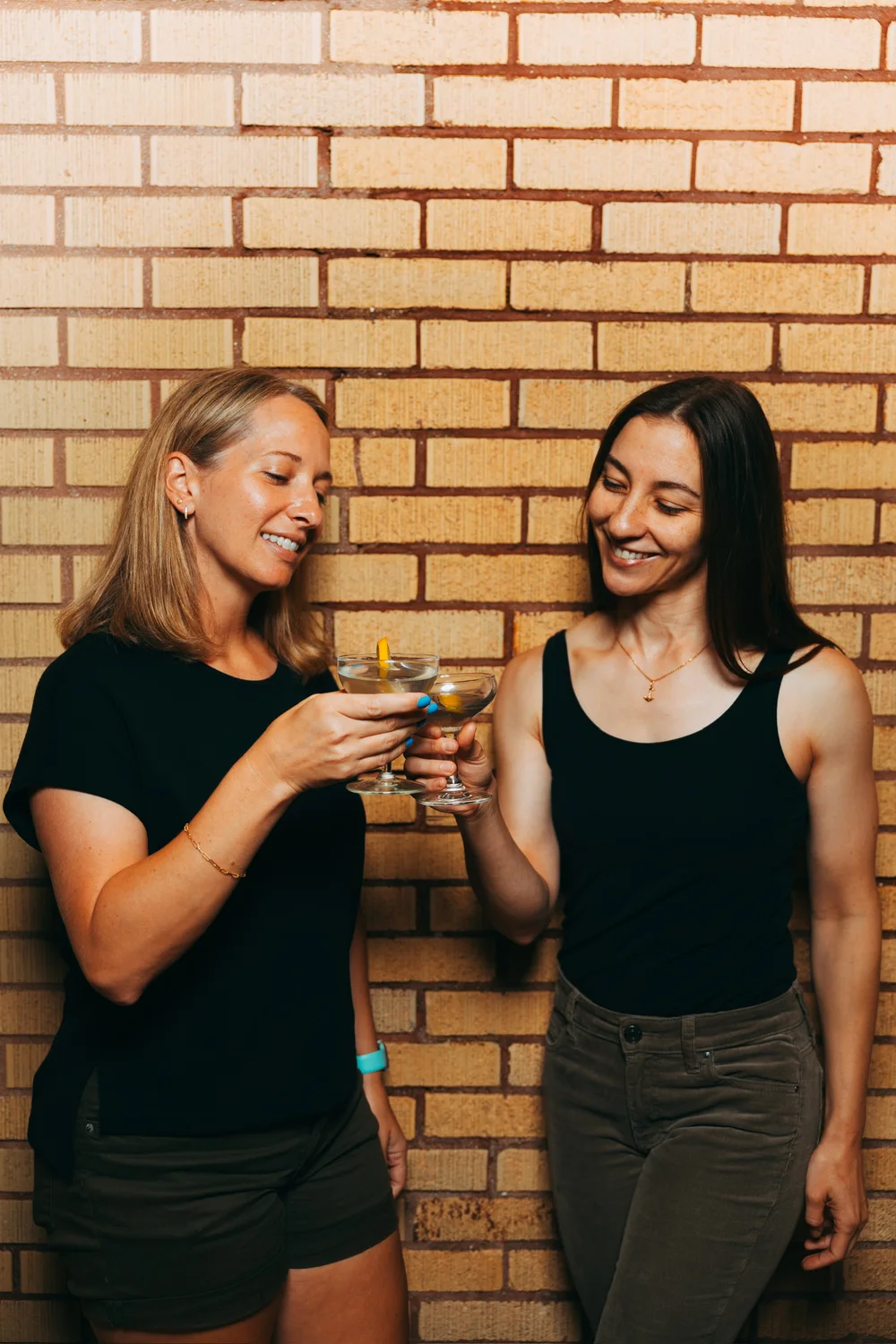 Two guests clinking coupes against the brick