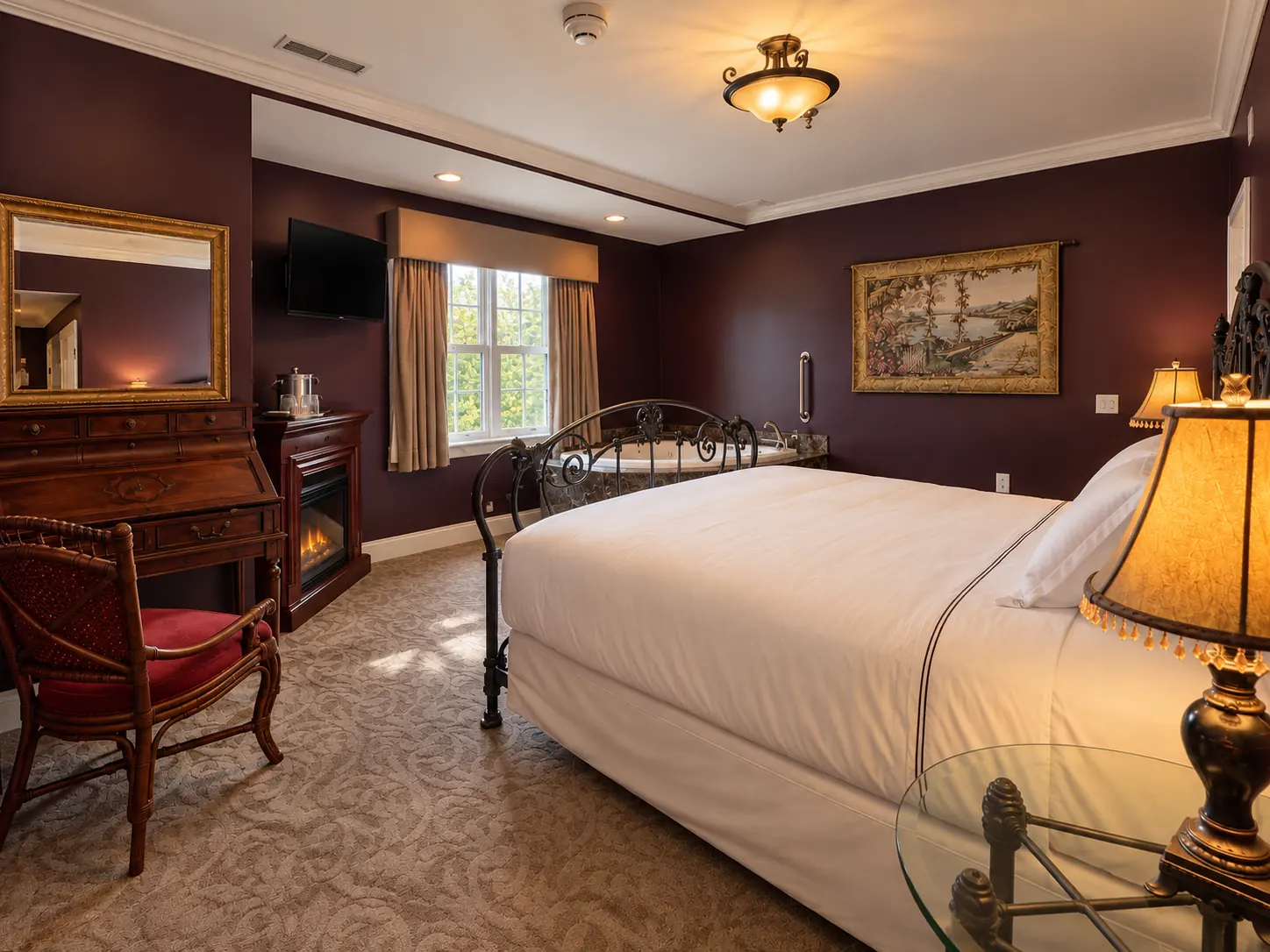 A king room in deep plum with an iron bed, a writing desk and a fireplace
